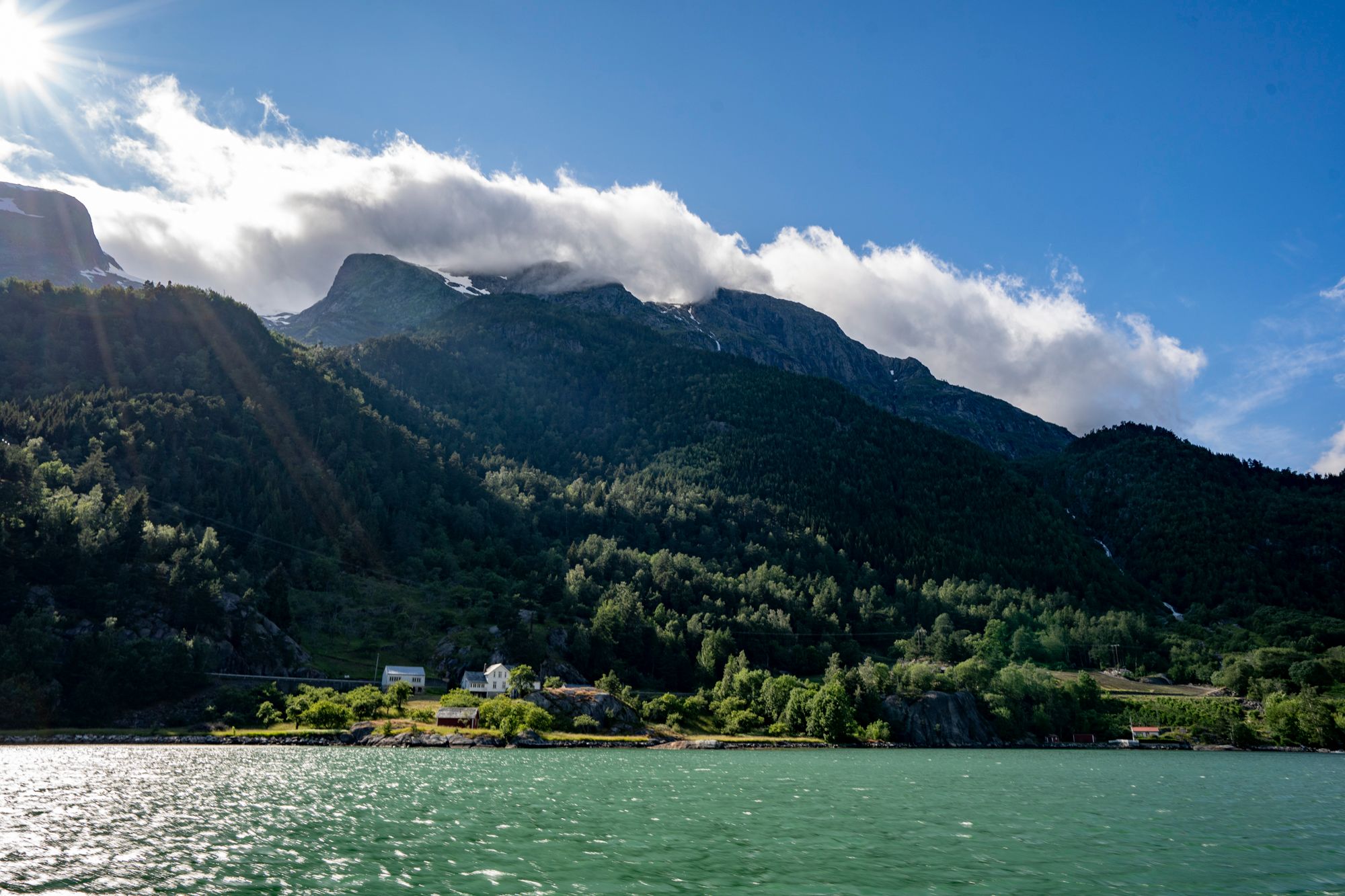 The Hardangerfjord glows under the sunlight, with majestic mountains in the background.