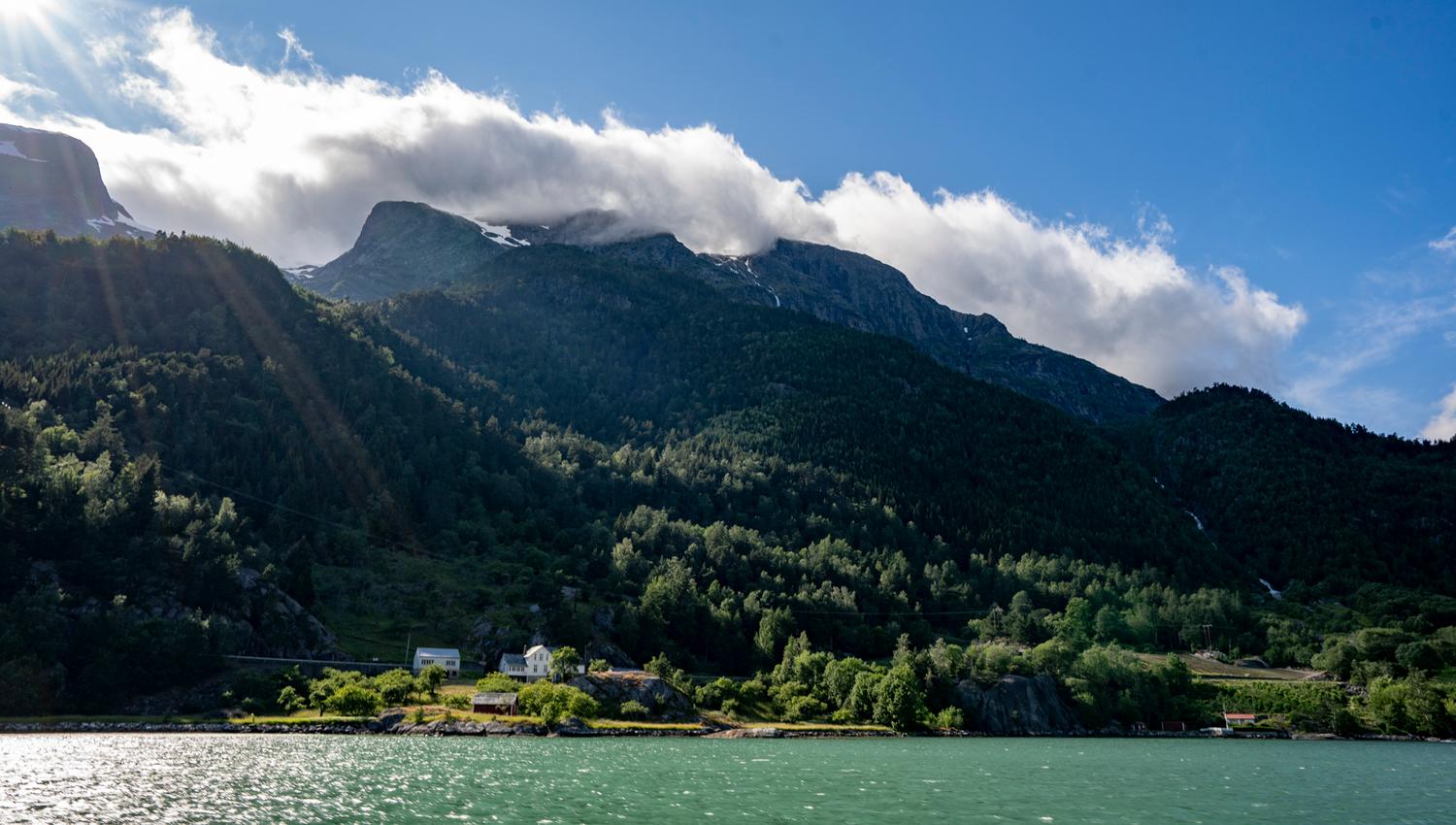 The Hardangerfjord glows under the sunlight, with majestic mountains in the background.