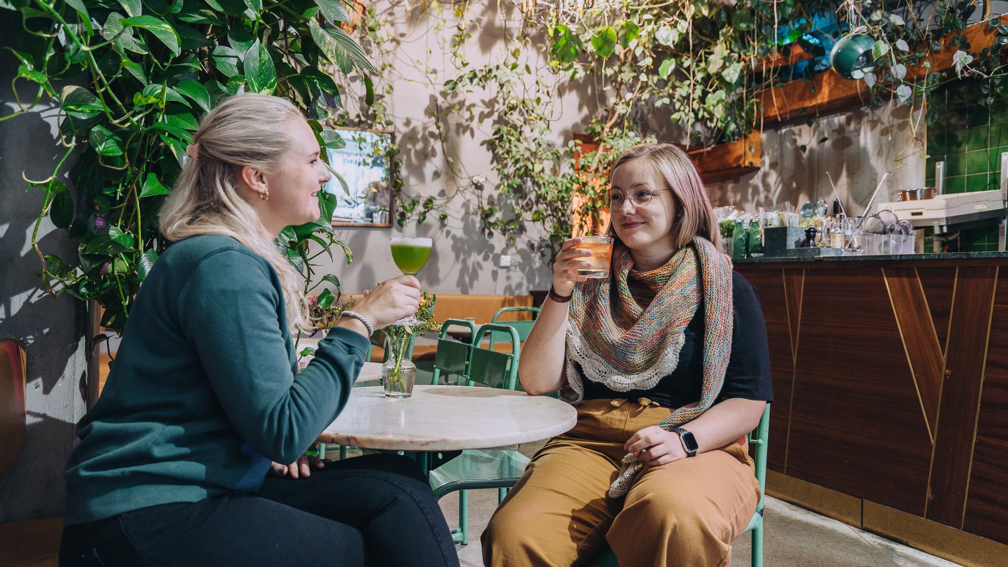Two girls drinking cocktails by the bar