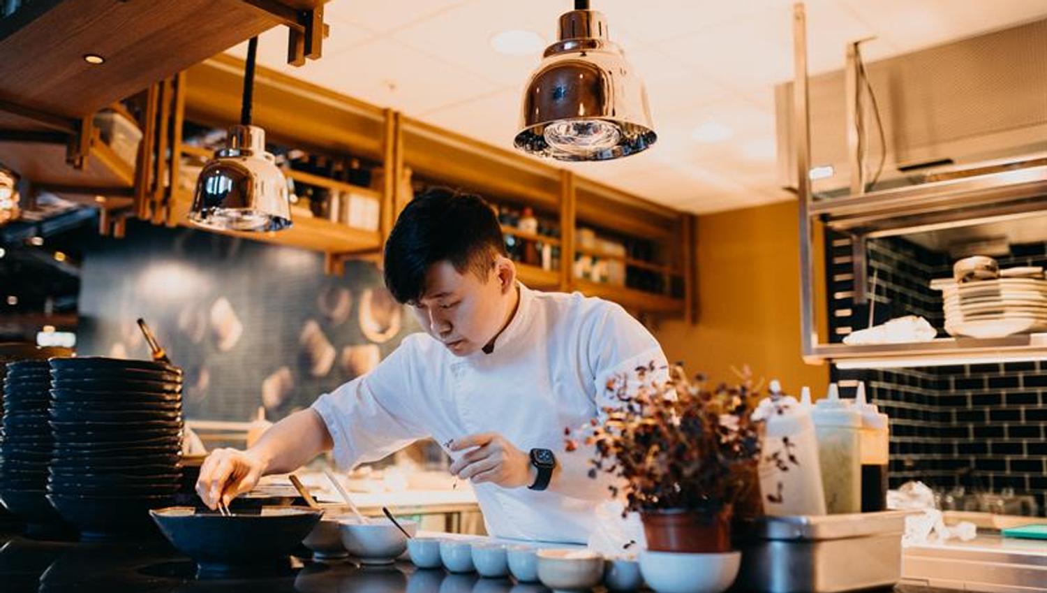 A cook preparing many small dishes in white bowls