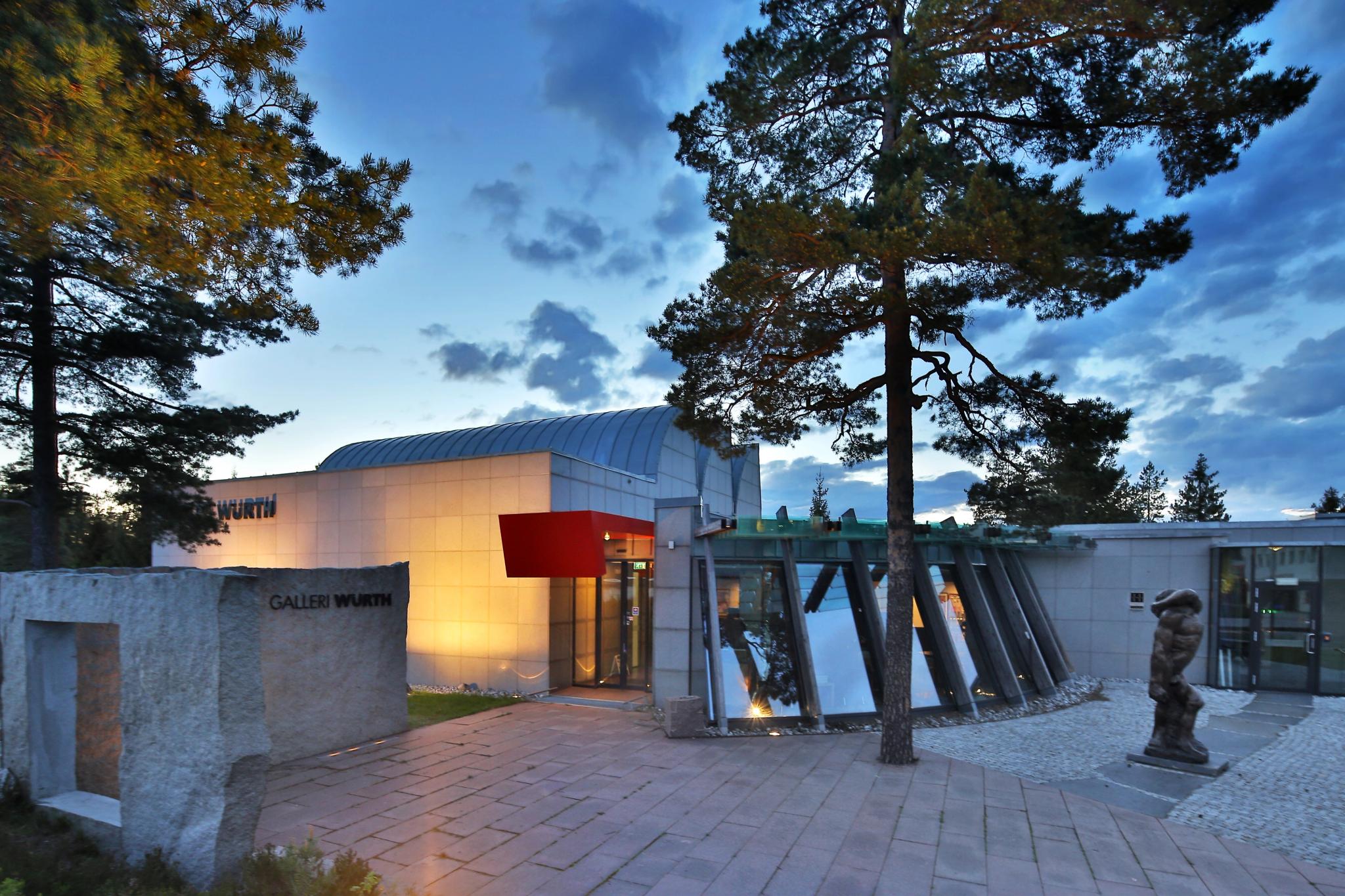 Fasaden av galleriet Würth i stein, glass og tre, med skulptur utenfor