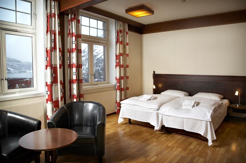 Romslig hotellrom med store vindauge, klassisk innreiing og utsikt mot Hardangerfjorden.