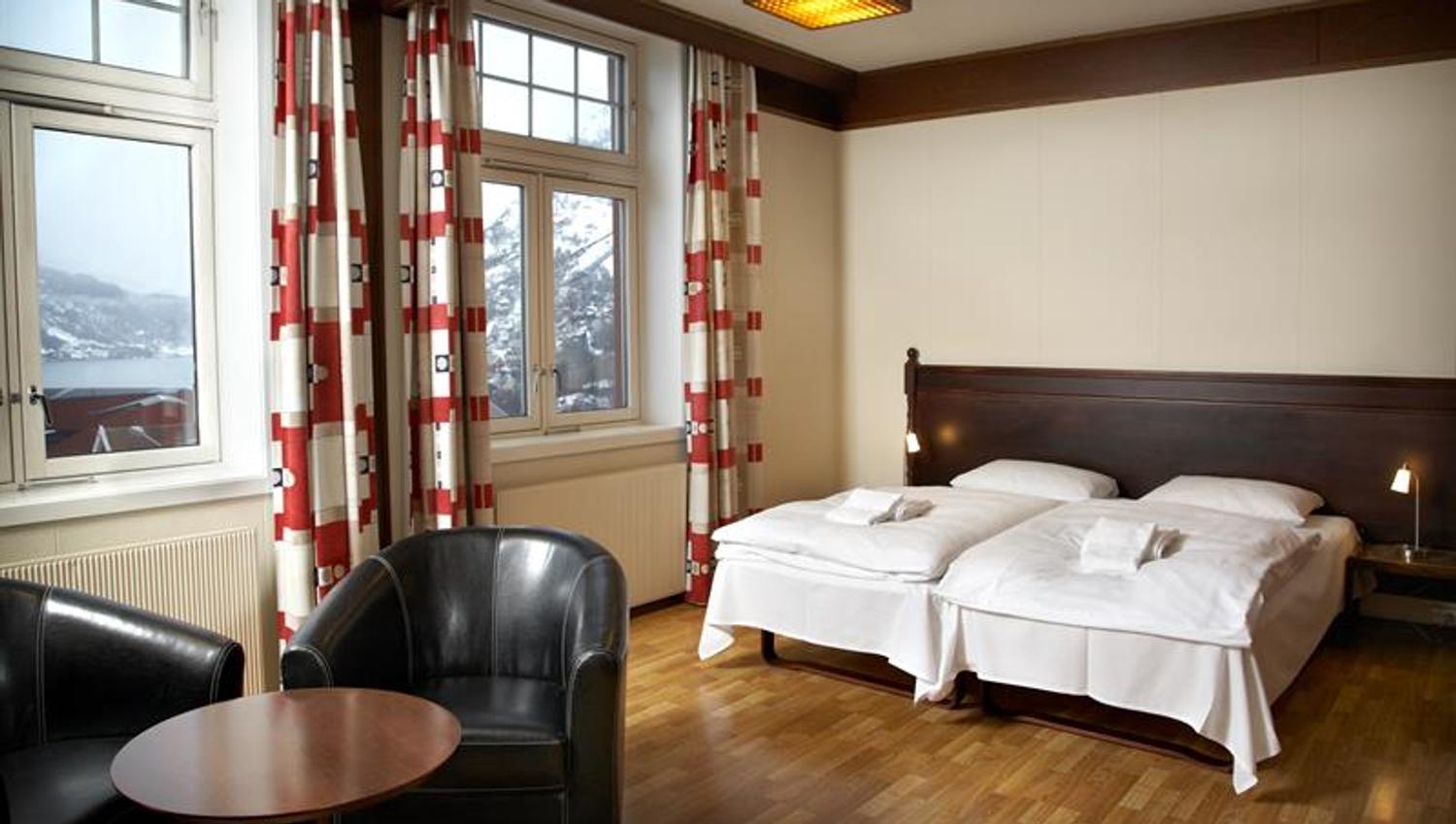 Romslig hotellrom med store vindauge, klassisk innreiing og utsikt mot Hardangerfjorden.