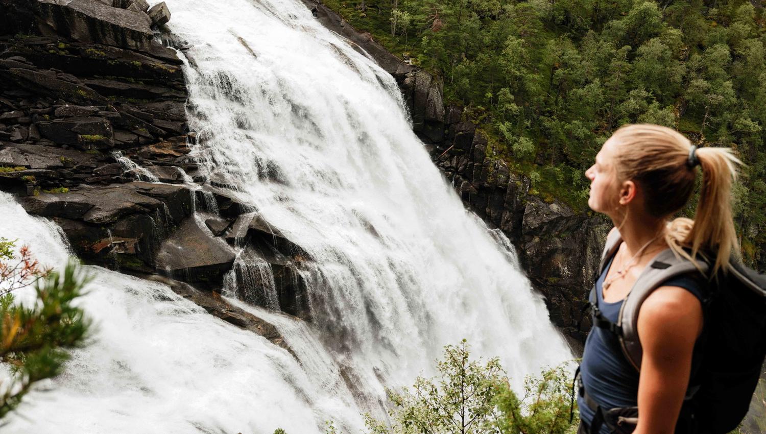 Nærbilete av turgåar med utsikt over Nykkjesøyfossen, ein av dei vakraste fossane i Husedalen.