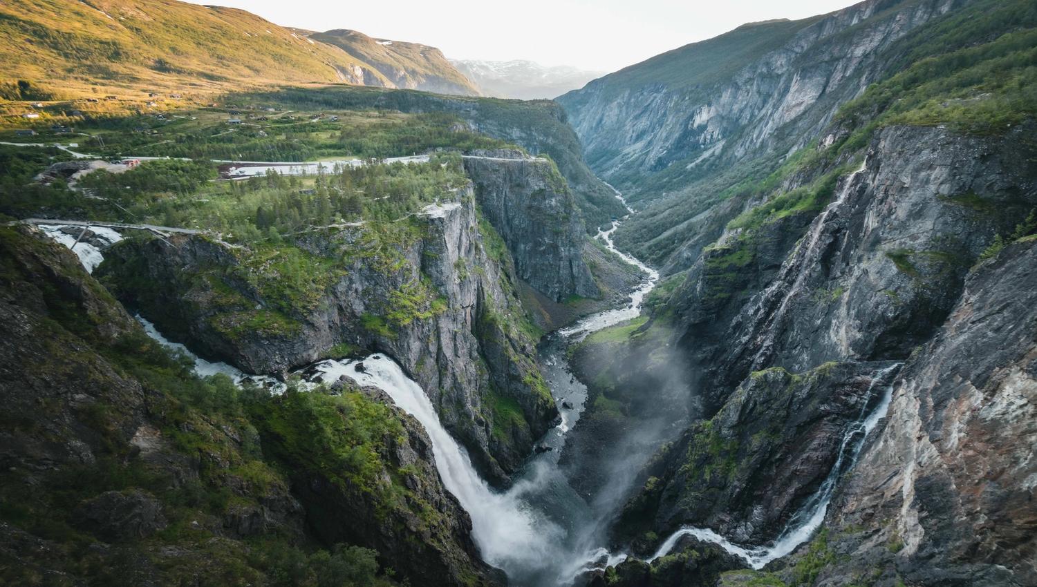 Vøringsfossen som fossar ned i Måbødalen, omgitt av bratte fjellsider og grøne dalsider i Hardanger.