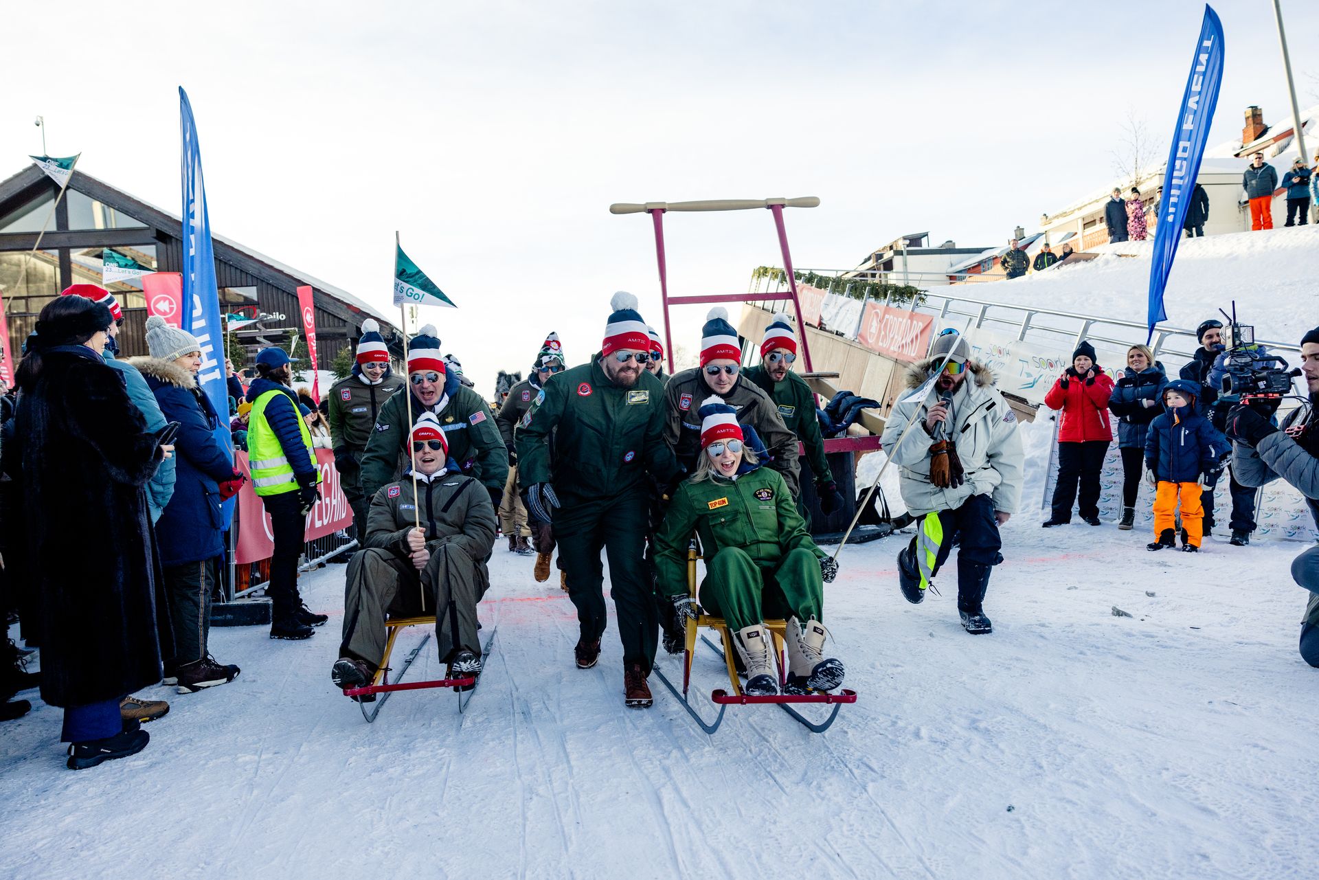 A large group of people participating in the Kicksled World Championship is sliding down the snow-