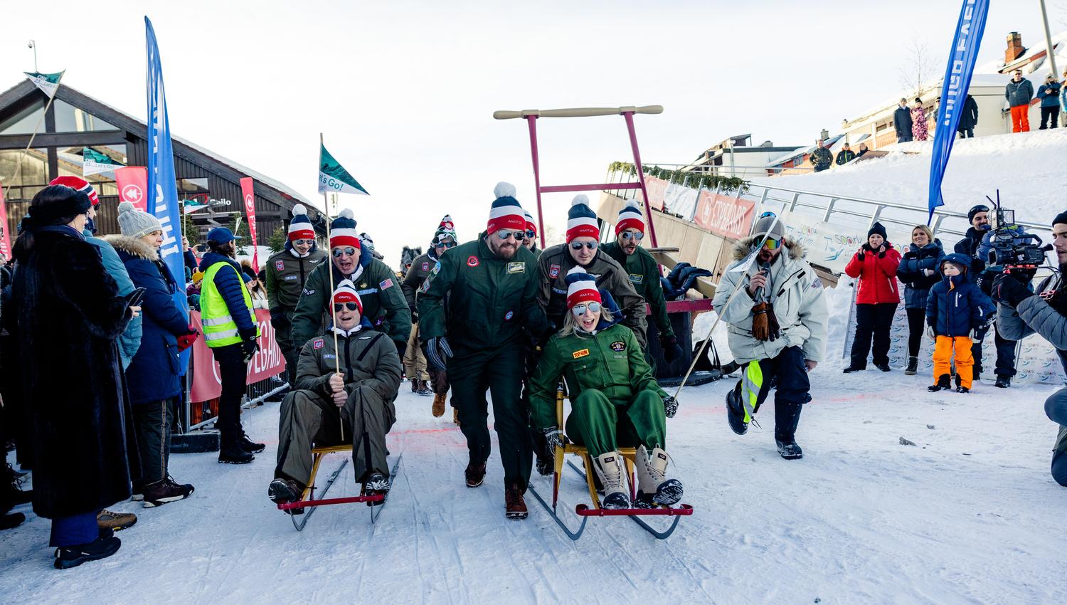 A large group of people participating in the Kicksled World Championship is sliding down the snow-