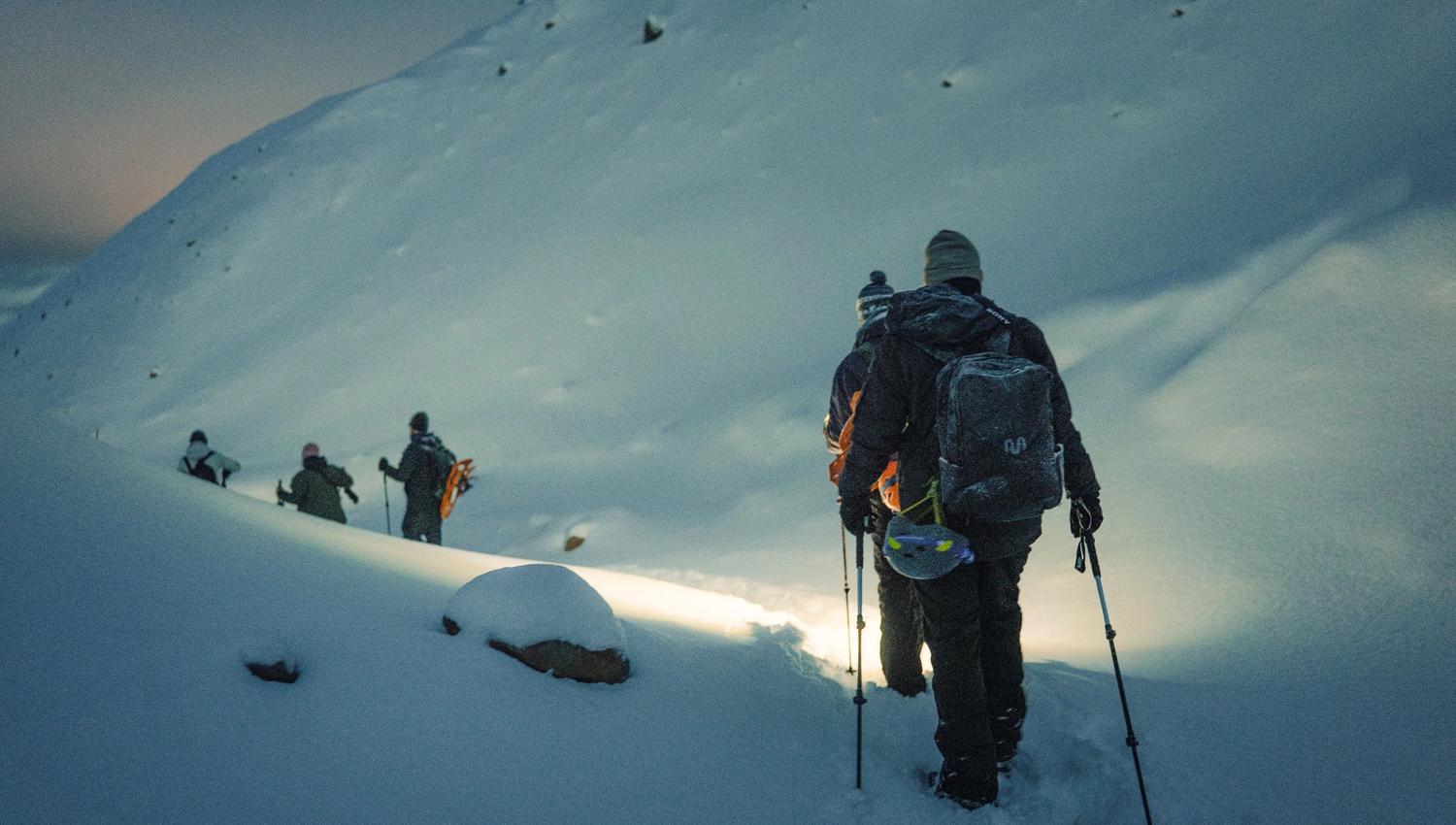 A group of people walking down a snow covered mountain