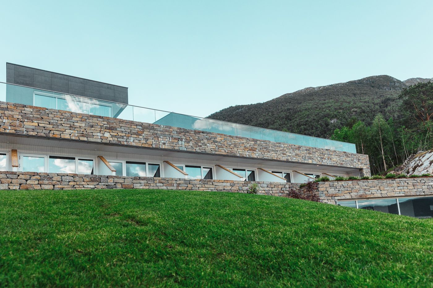Natural stone walls at Hardanger House blended with lush landscape.