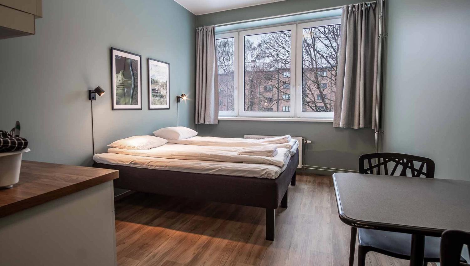 Privatrom med dobbeltseng, kjøkken, spisebord og vindu