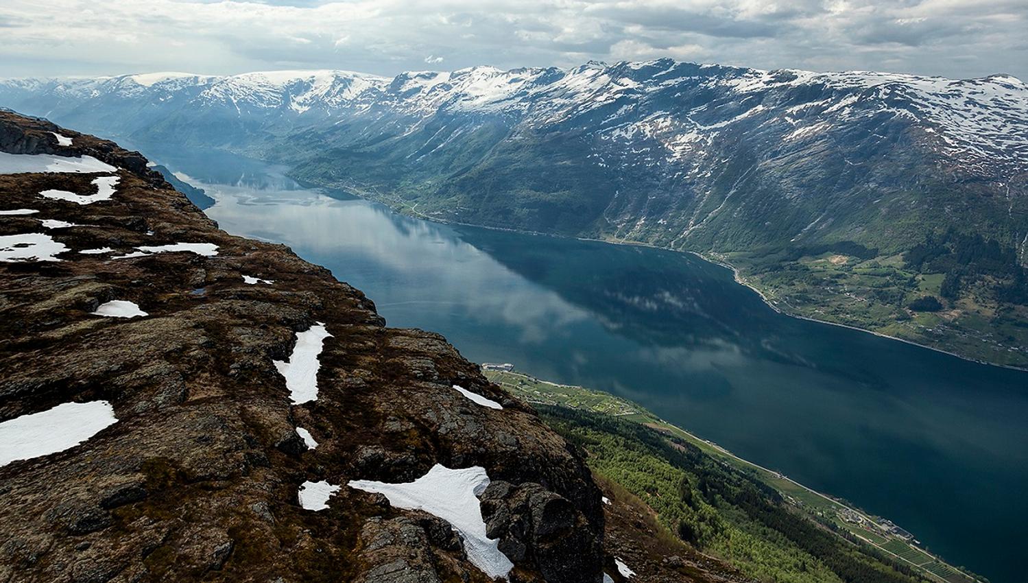 View from Dronningstien over the Hardangerfjord with snow-capped mountains in the background.