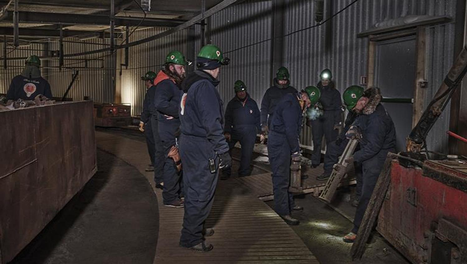 Guests on a guided tour of Mine 3 lifting and feeling the weight of mine pistons/pillars that were used there