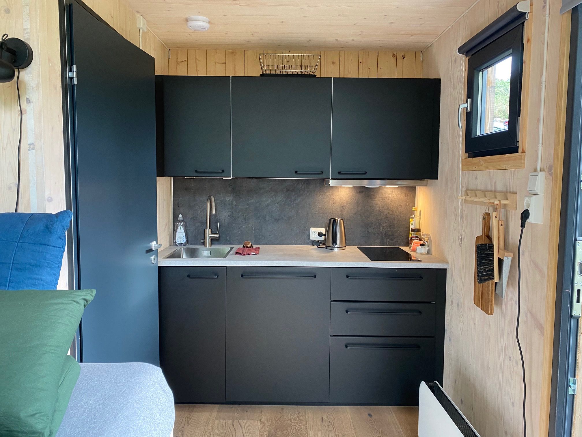 Modern kitchen in the cabin with black cabinet doors and wooden walls.