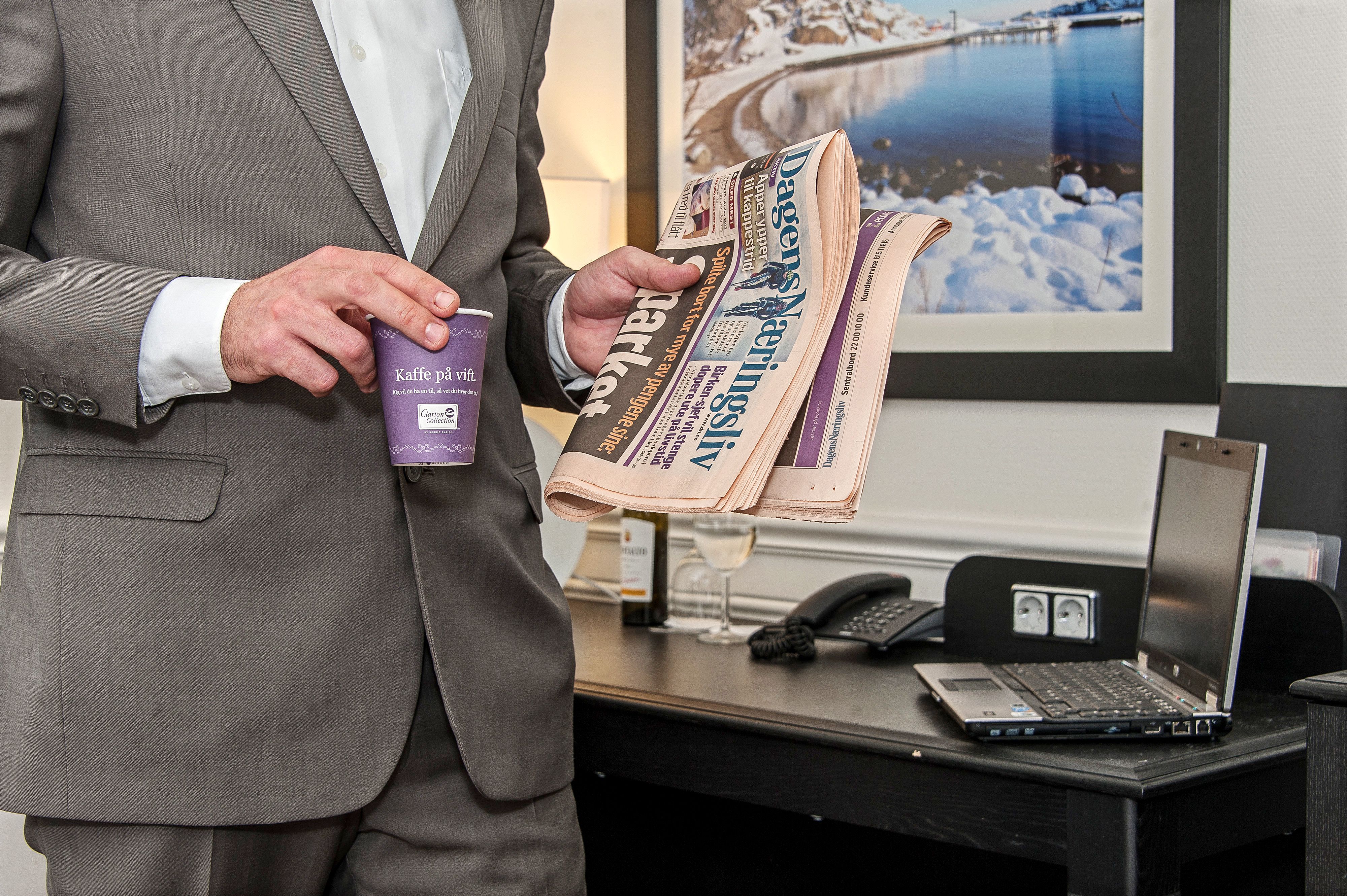 Person with coffee and newspaper in hand