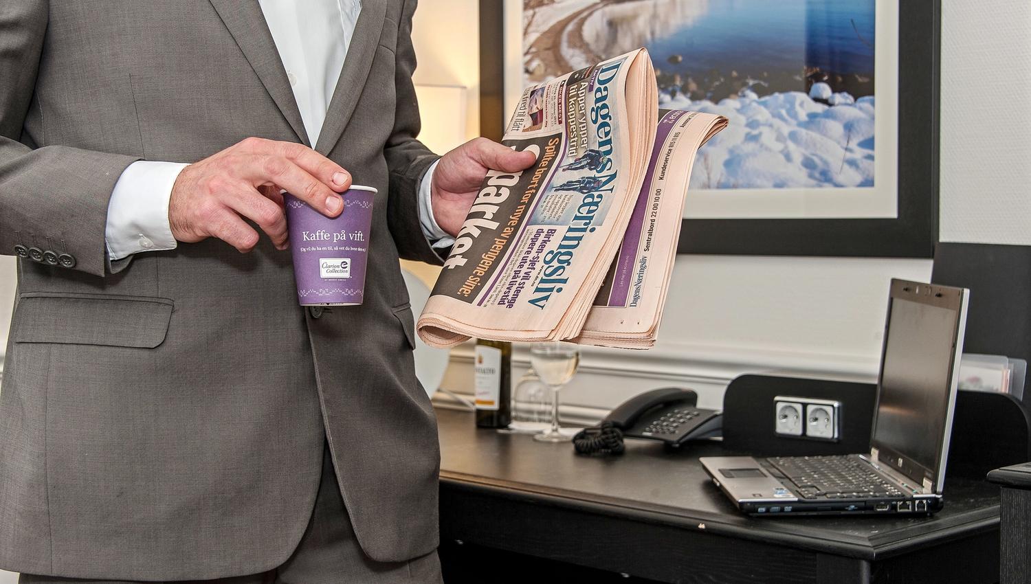 Person with coffee and newspaper in hand