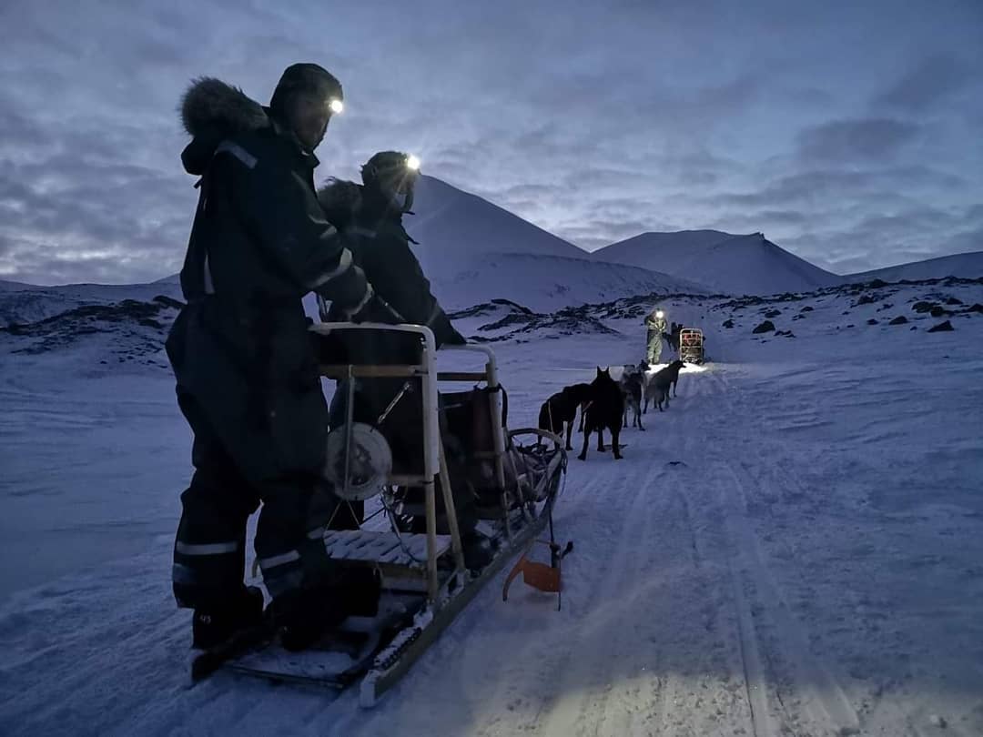 Two persons on a dog sled looking backwards into the camera