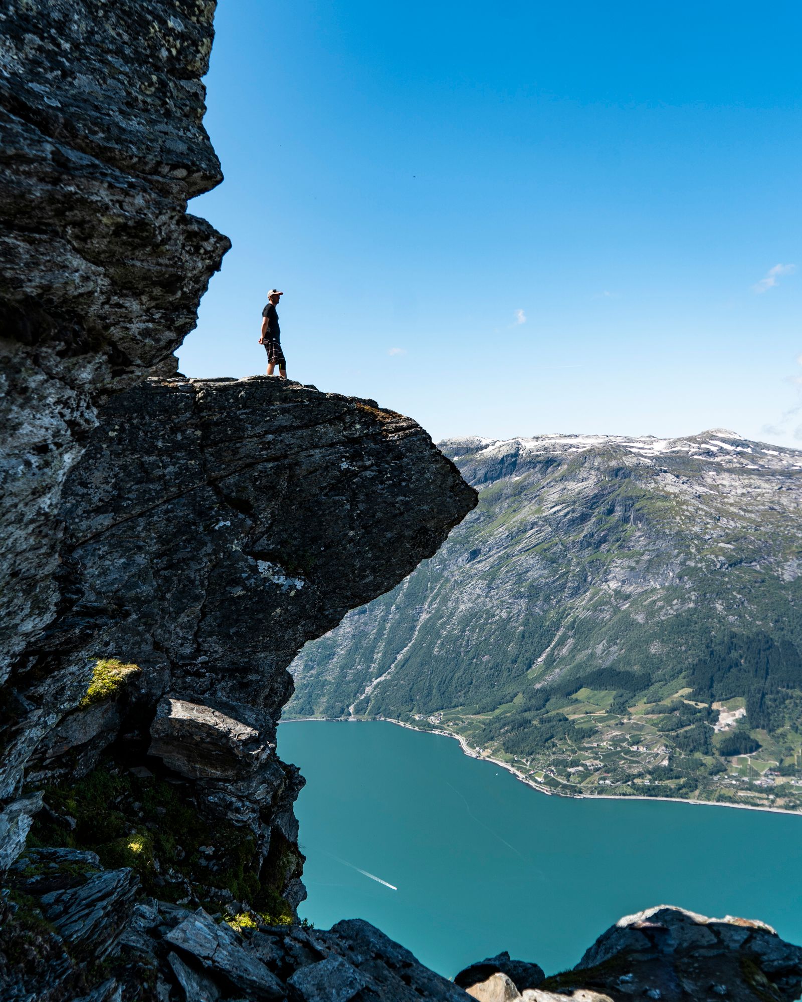 Tourist exploring "mini trolltunga" on the Dronningstien Hike in Hardanger.