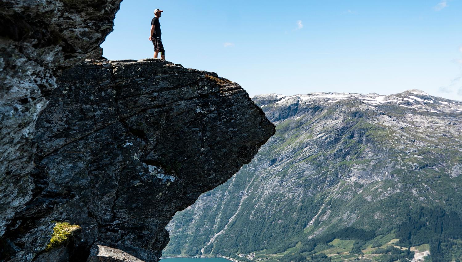 Tourist exploring "mini trolltunga" on the Dronningstien Hike in Hardanger.