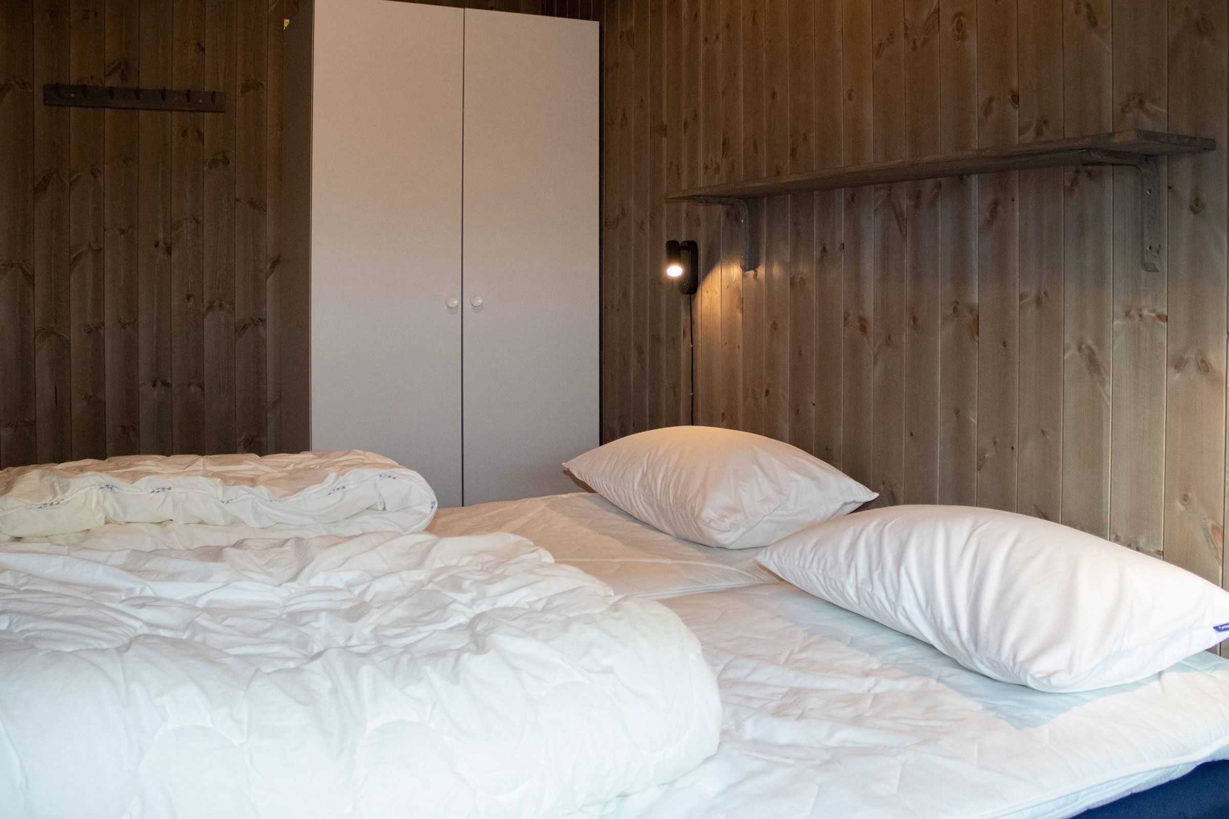 A bed with white sheets and pillows.