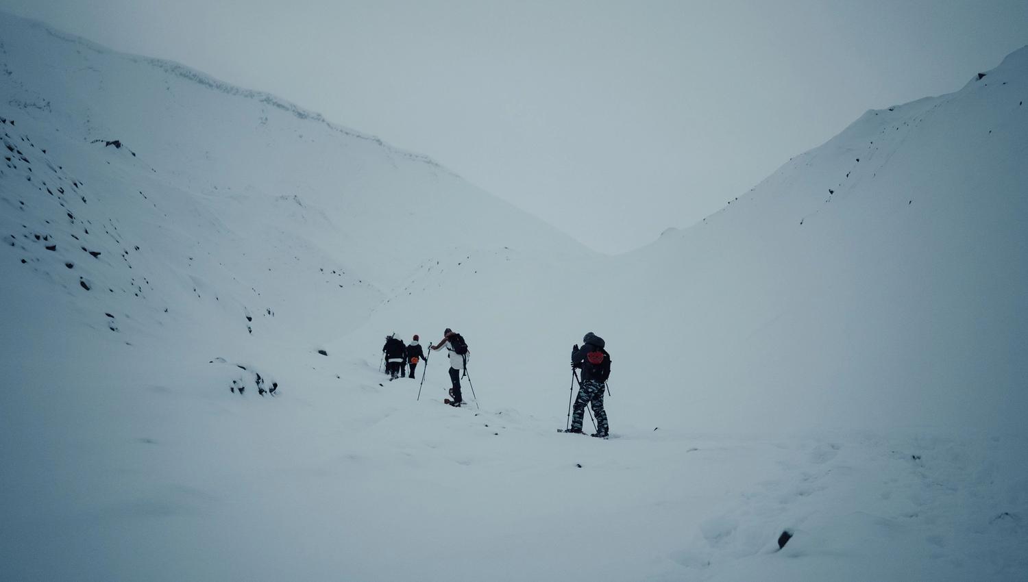 A group of people walking up a mountain with snowshoes