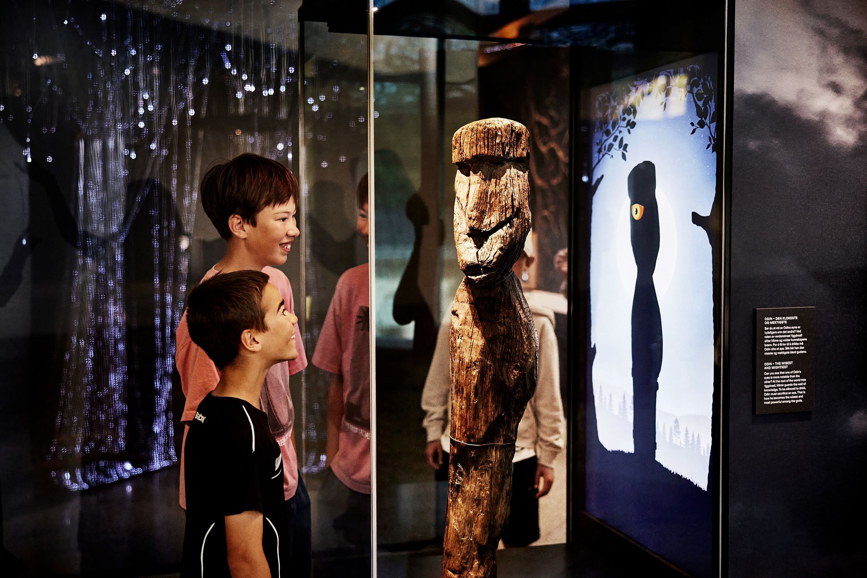 Two children looking at a wooden figure of Odin on display