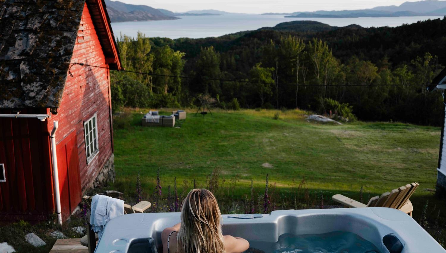 Kvinne slappar av i utespa med utsikt over Hardangerfjorden på Stigen Fjordlodge.
