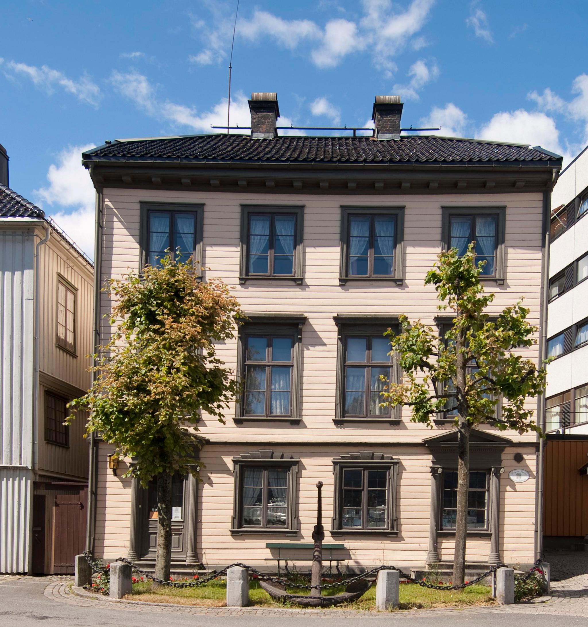 Fasade på Kløckers Hus - Arendal Bymuseum. treetasjes hus malt i beige med brune vinduskarmer
