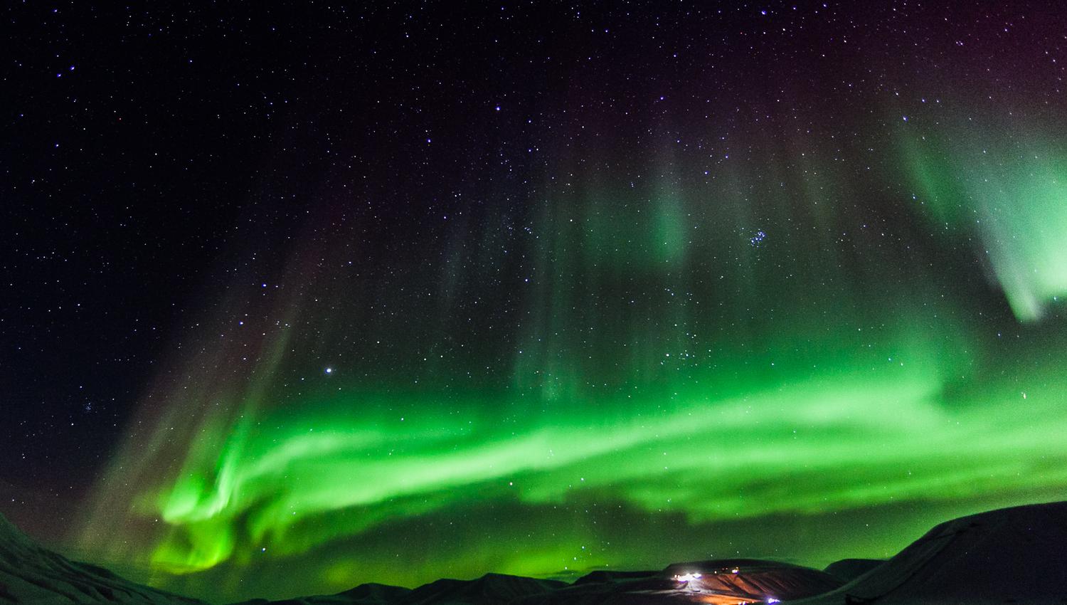 Nordlys som skinner på himmelen over en dal