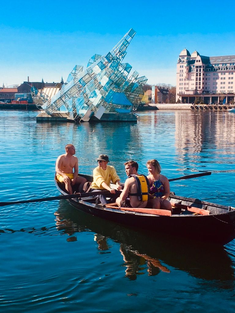 A group in a Færing boat in front of the installation "She Lies"