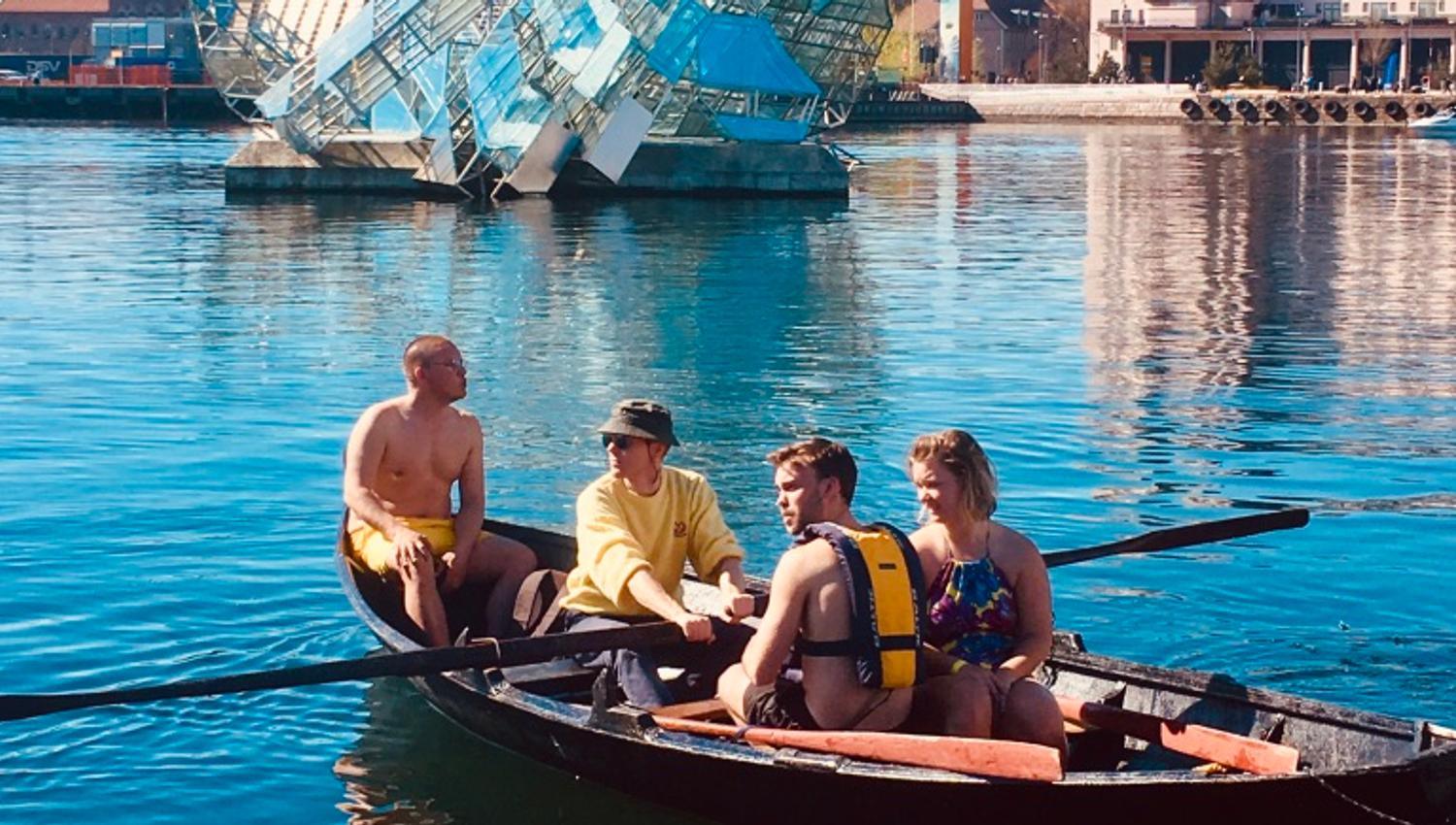 A group in a Færing boat in front of the installation "She Lies"