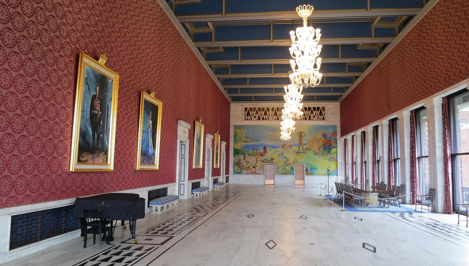 one of the hallways in oslo city hall with chandeliers from the ceiling and large paintings