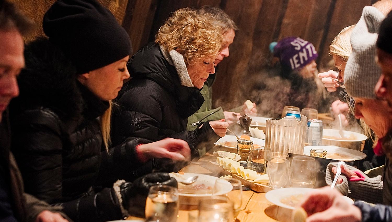 Guests eating dinner inside the cabin at Camp Barentz