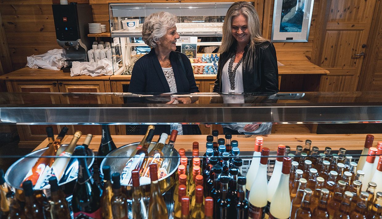 Two women looking at the display of various bottles of apple juice and other soft drinks at the Hardangerviddahallen restaurant.