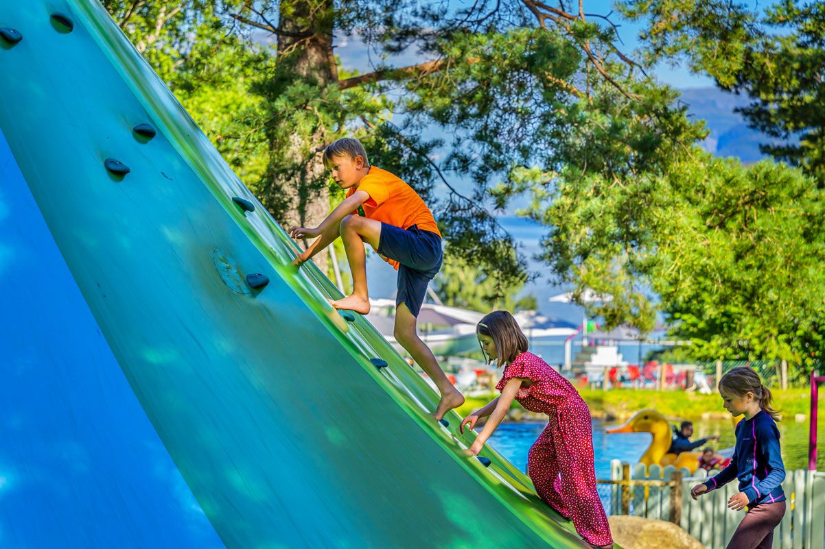 Children climbing a large blue climbing wall in the play area