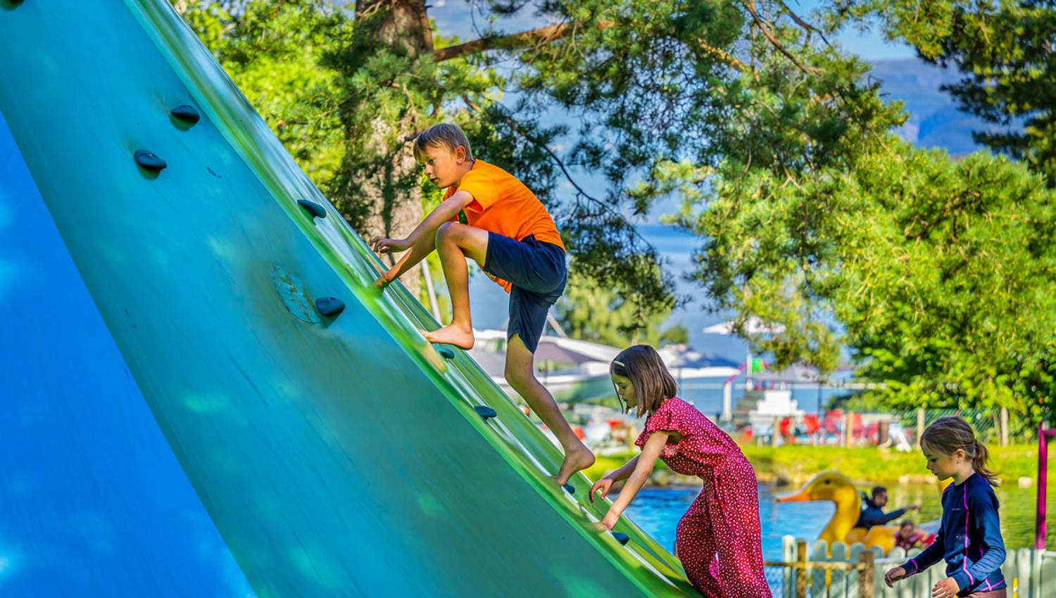Children climbing a large blue climbing wall in the play area