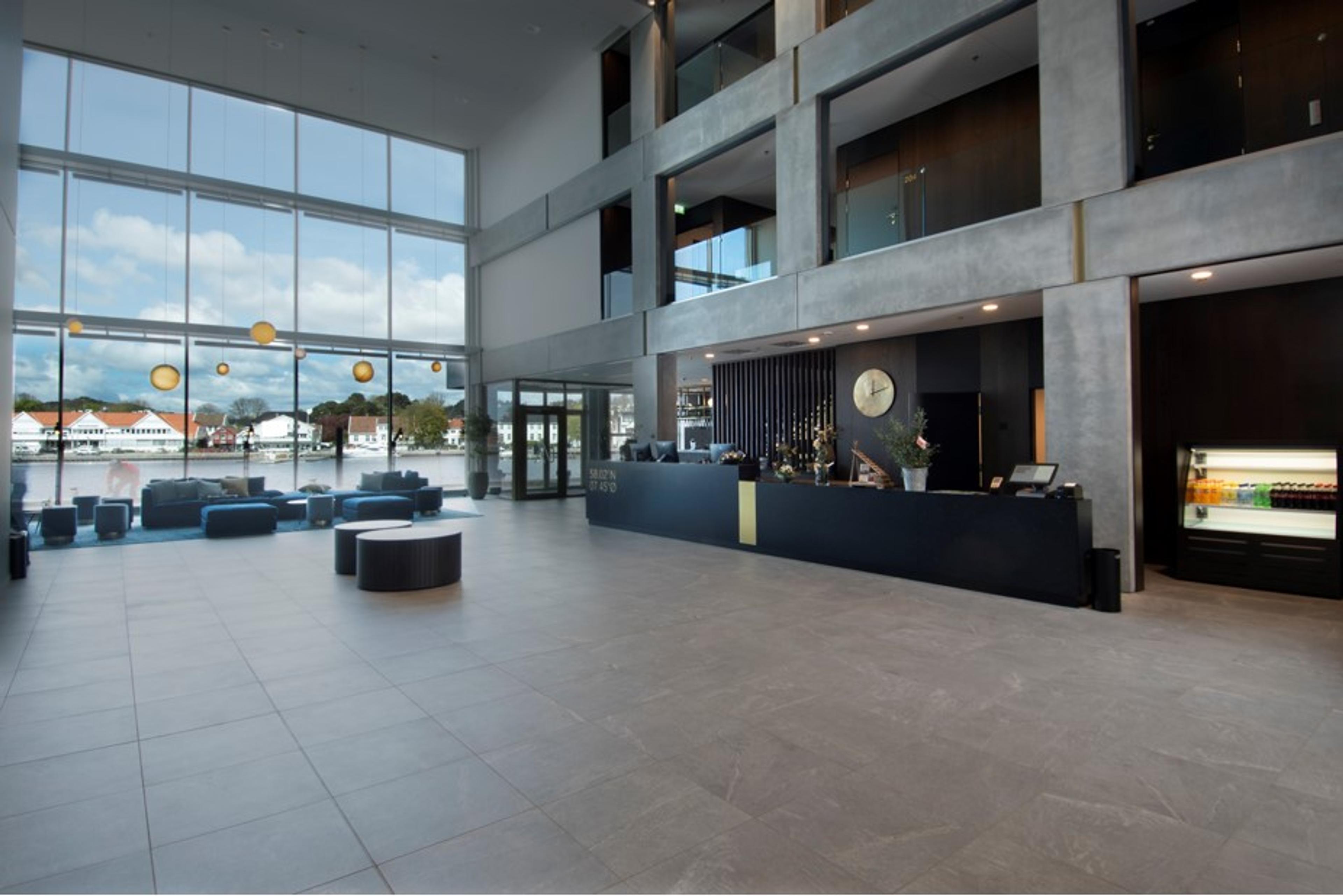 Inngangen, svart resepsjon, alt er i grått med en hel vegg med vindu utsikt mot vannet