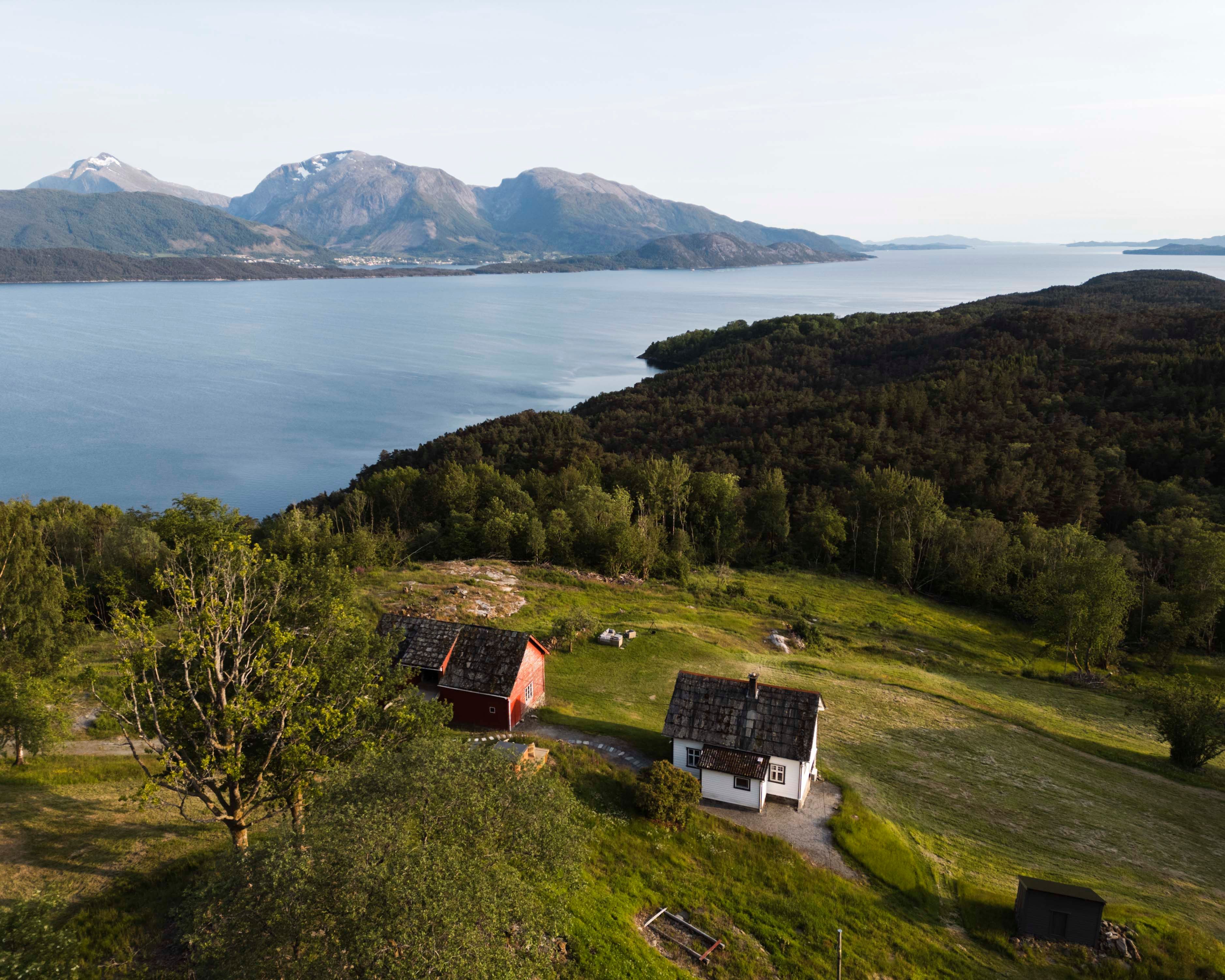 Dronebilde av Stigen Fjordlodge med fjord og fjell i Hardanger.