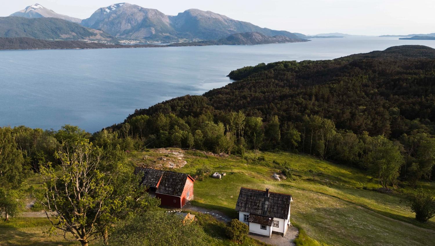 Dronebilde av Stigen Fjordlodge med fjord og fjell i Hardanger.