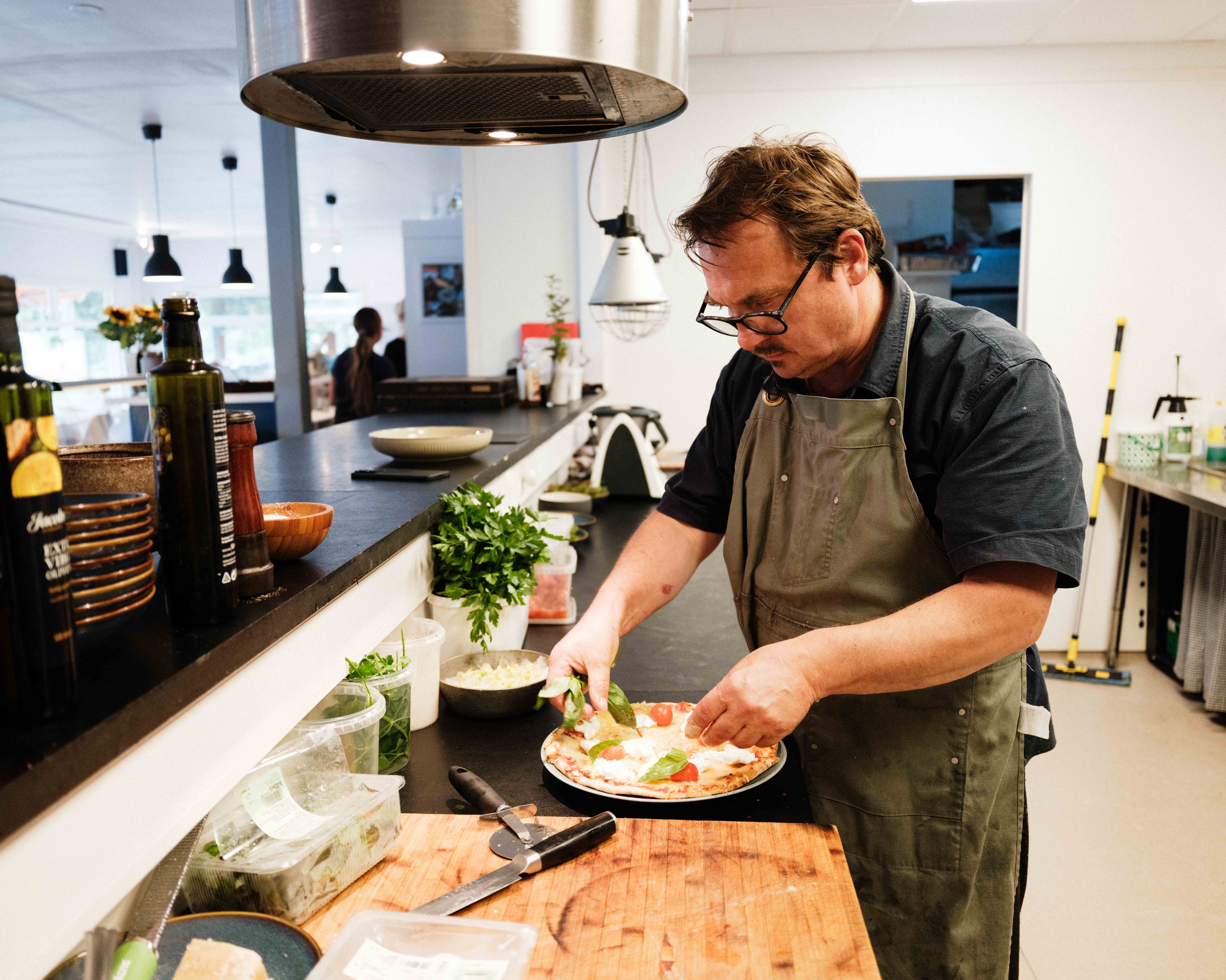 Kokk legg siste hand på ein rykande fersk pizza på Gløyp Spiseri i Kinsarvik.