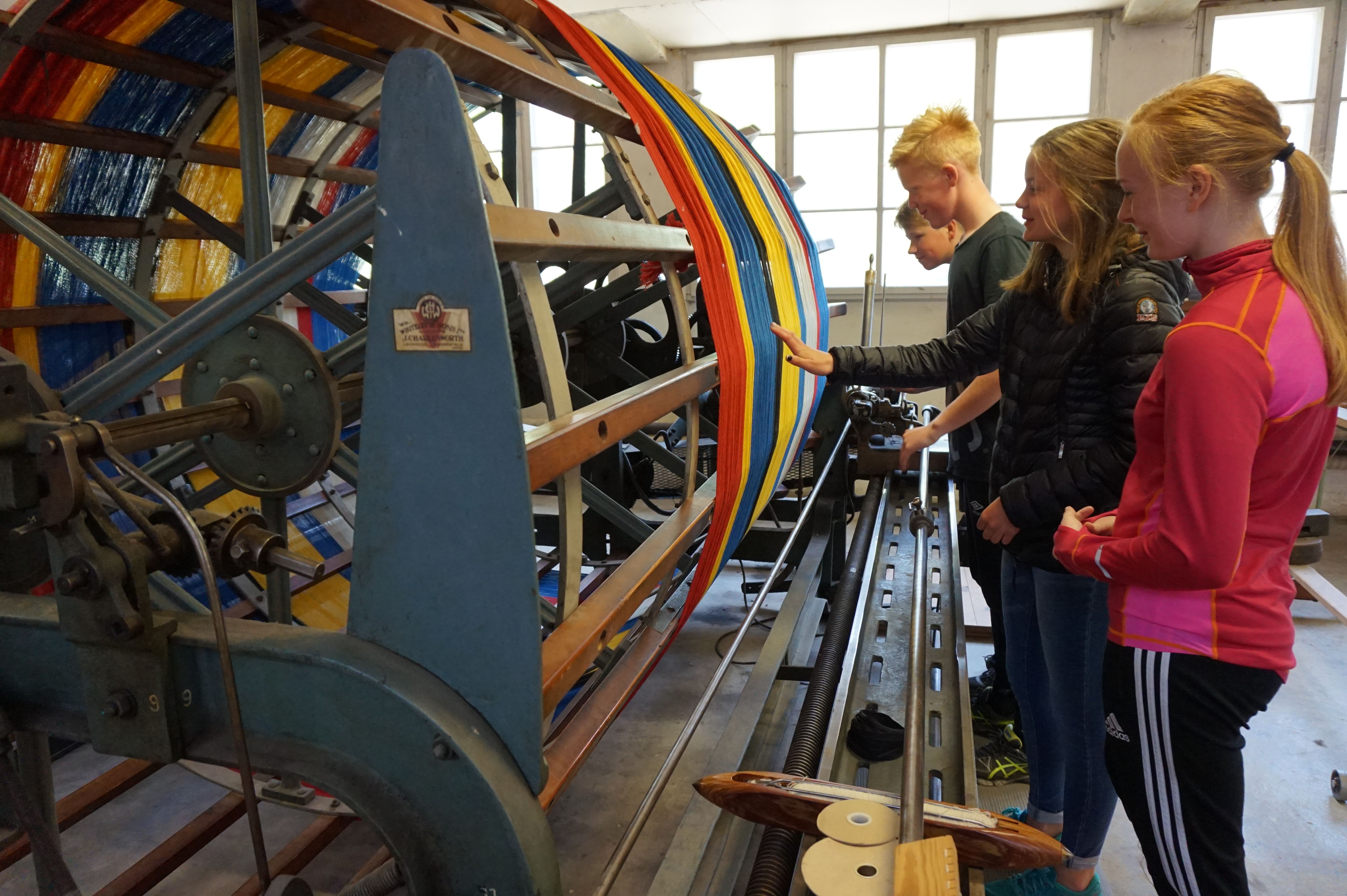 Group of children feeling new yarn: red, yellow, blue.