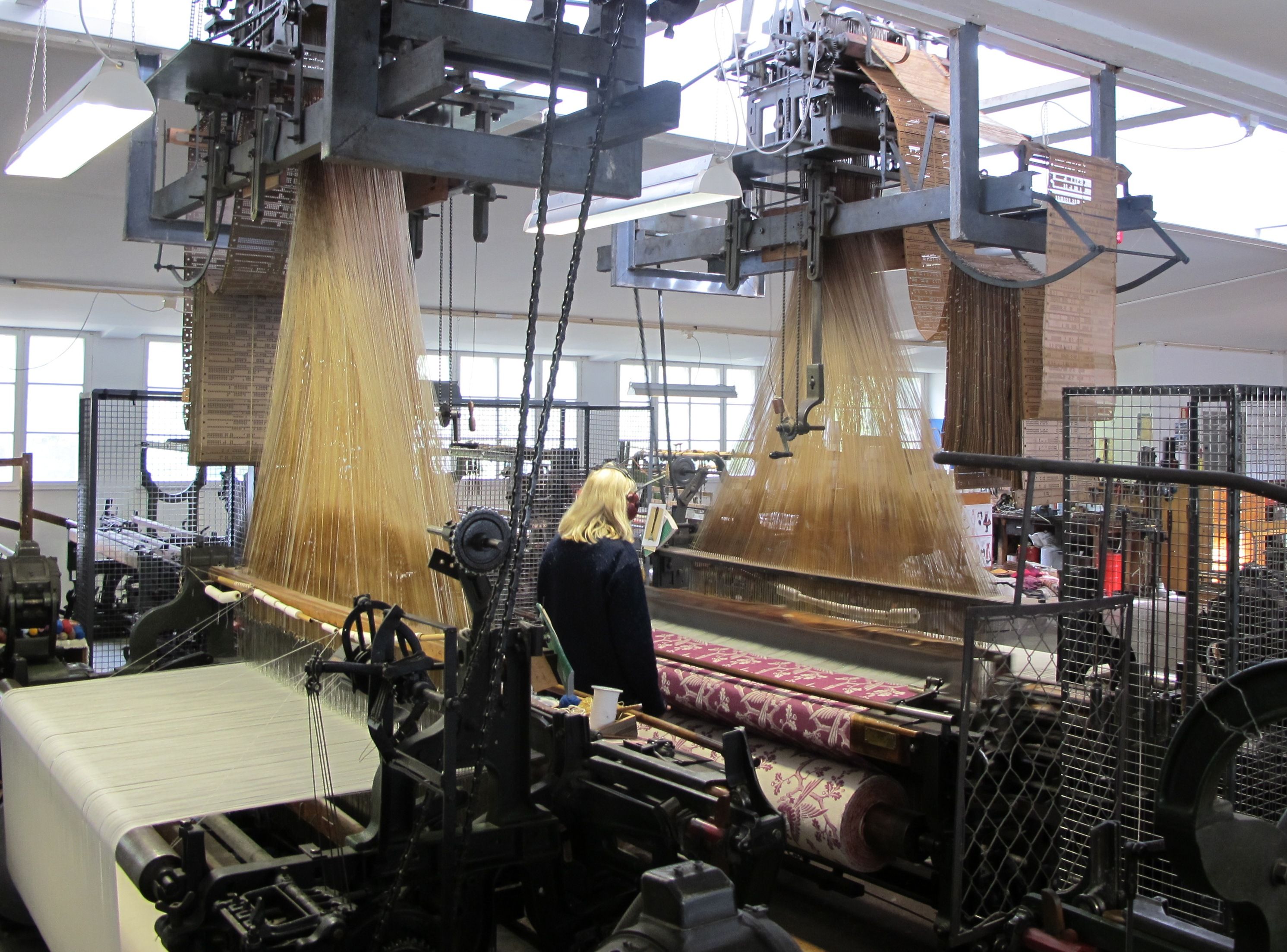 Inside uldvarefabriken (the wool factory), machines weaving carpets