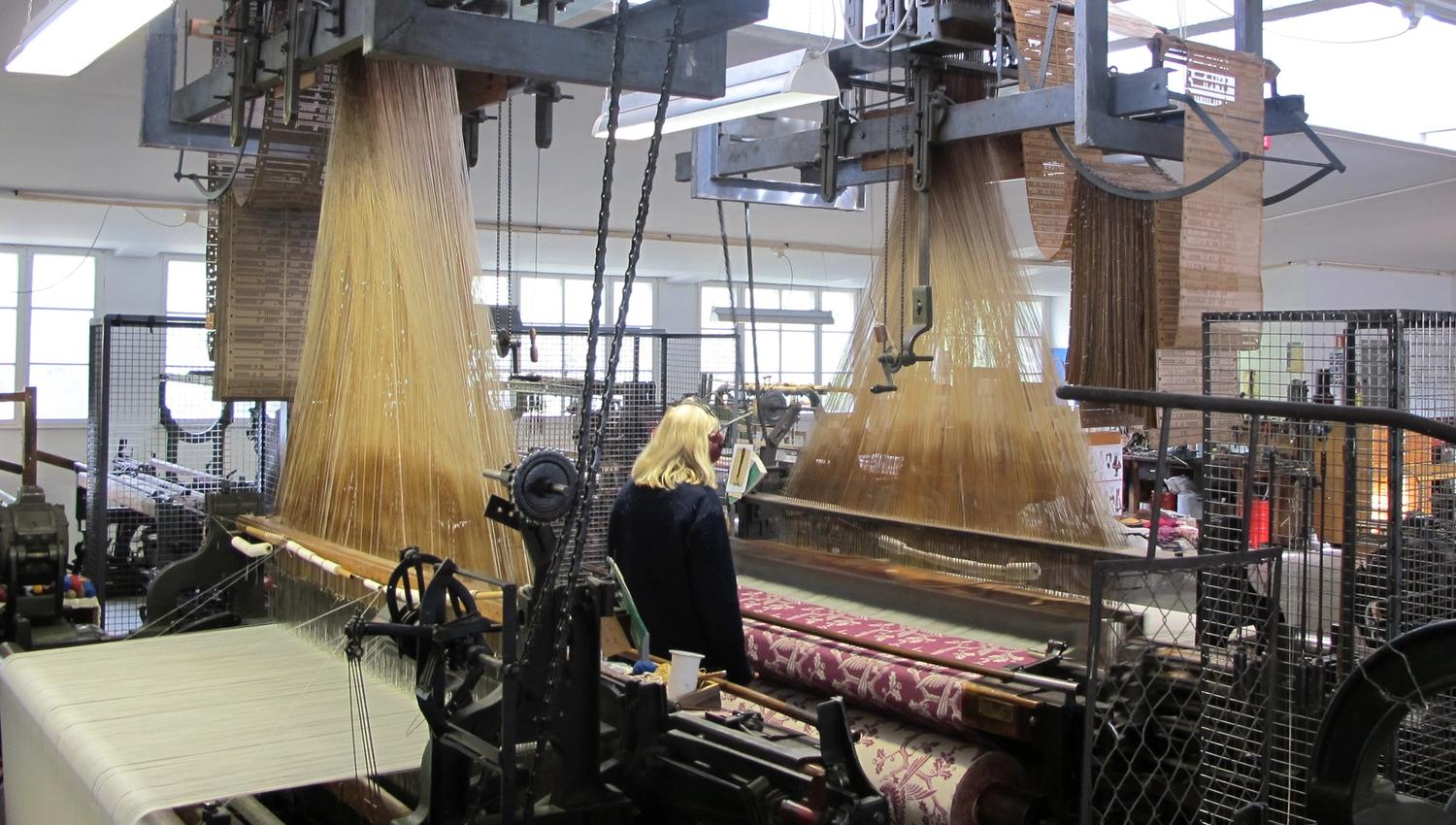 Inside uldvarefabriken (the wool factory), machines weaving carpets