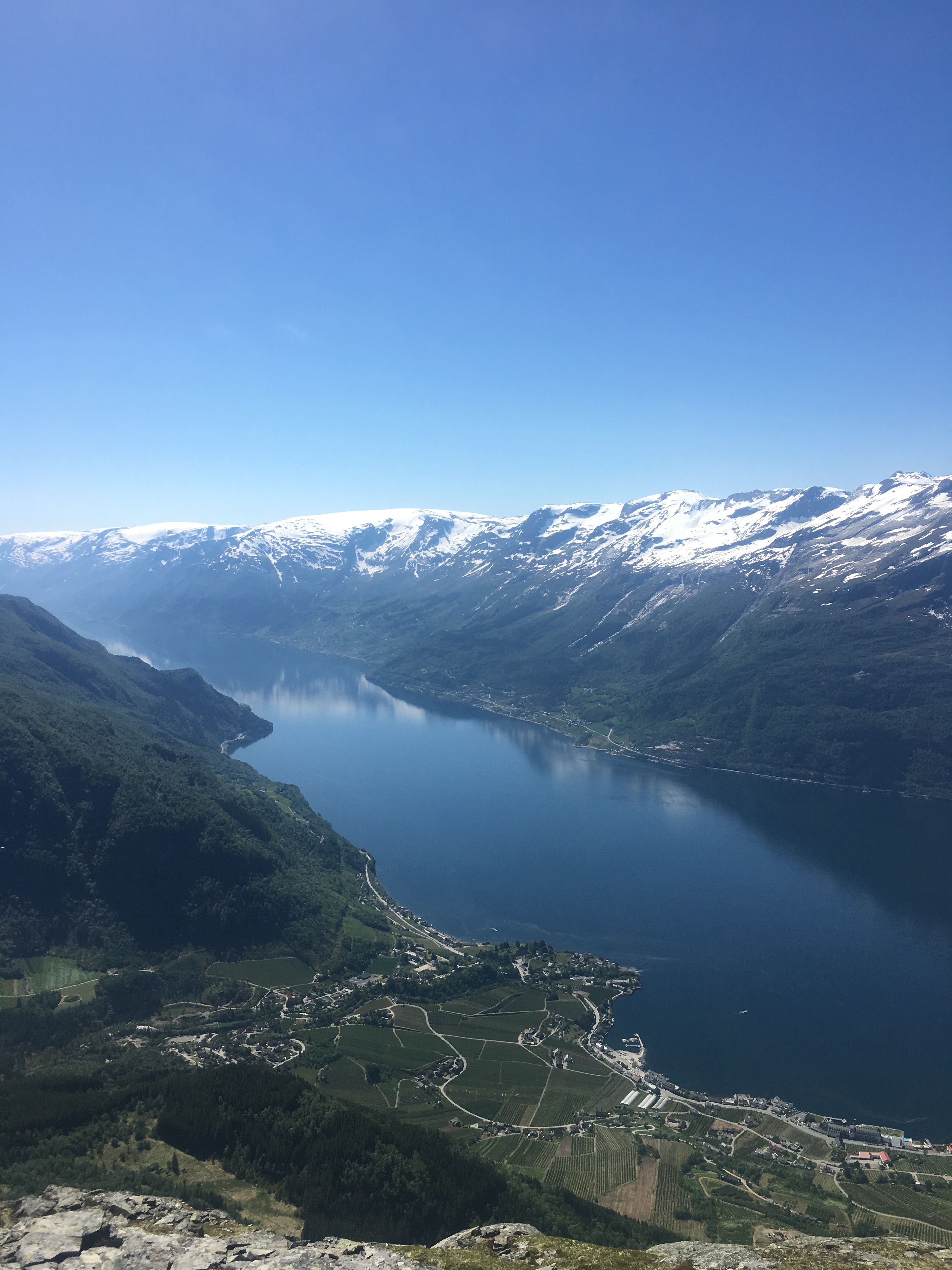 Panoramic view of the Hardangerfjord with villages and snow-capped mountains.