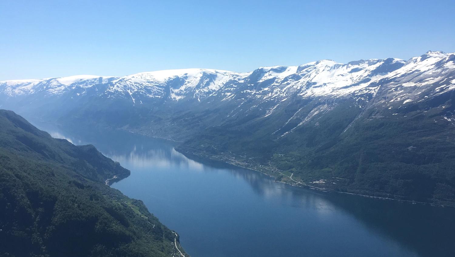 Panoramic view of the Hardangerfjord with villages and snow-capped mountains.