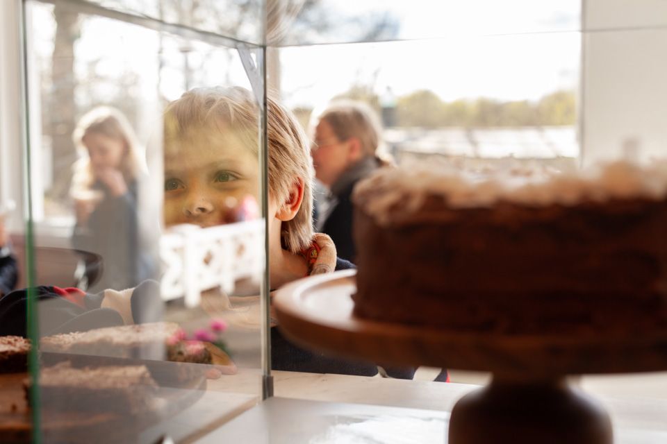 Et barn ser i et vitrinenskap med kake