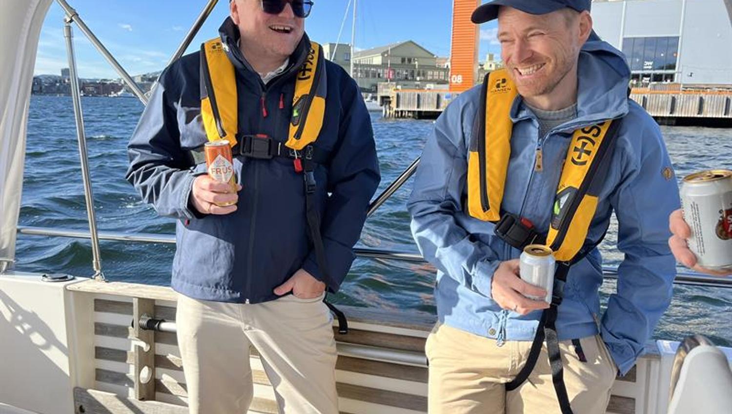 To glade båtgjester med redningsvester på dekk