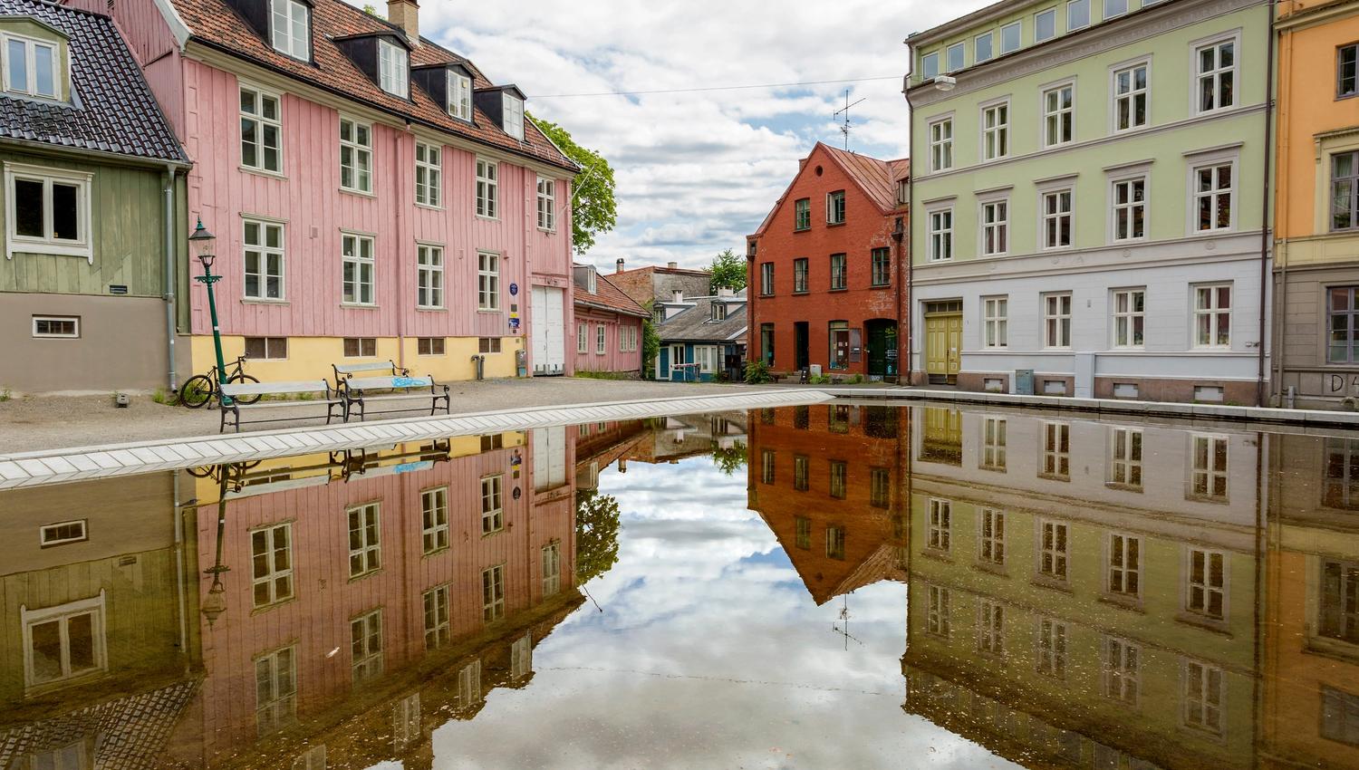 Gamle trehus rundt en plass med et basseng.