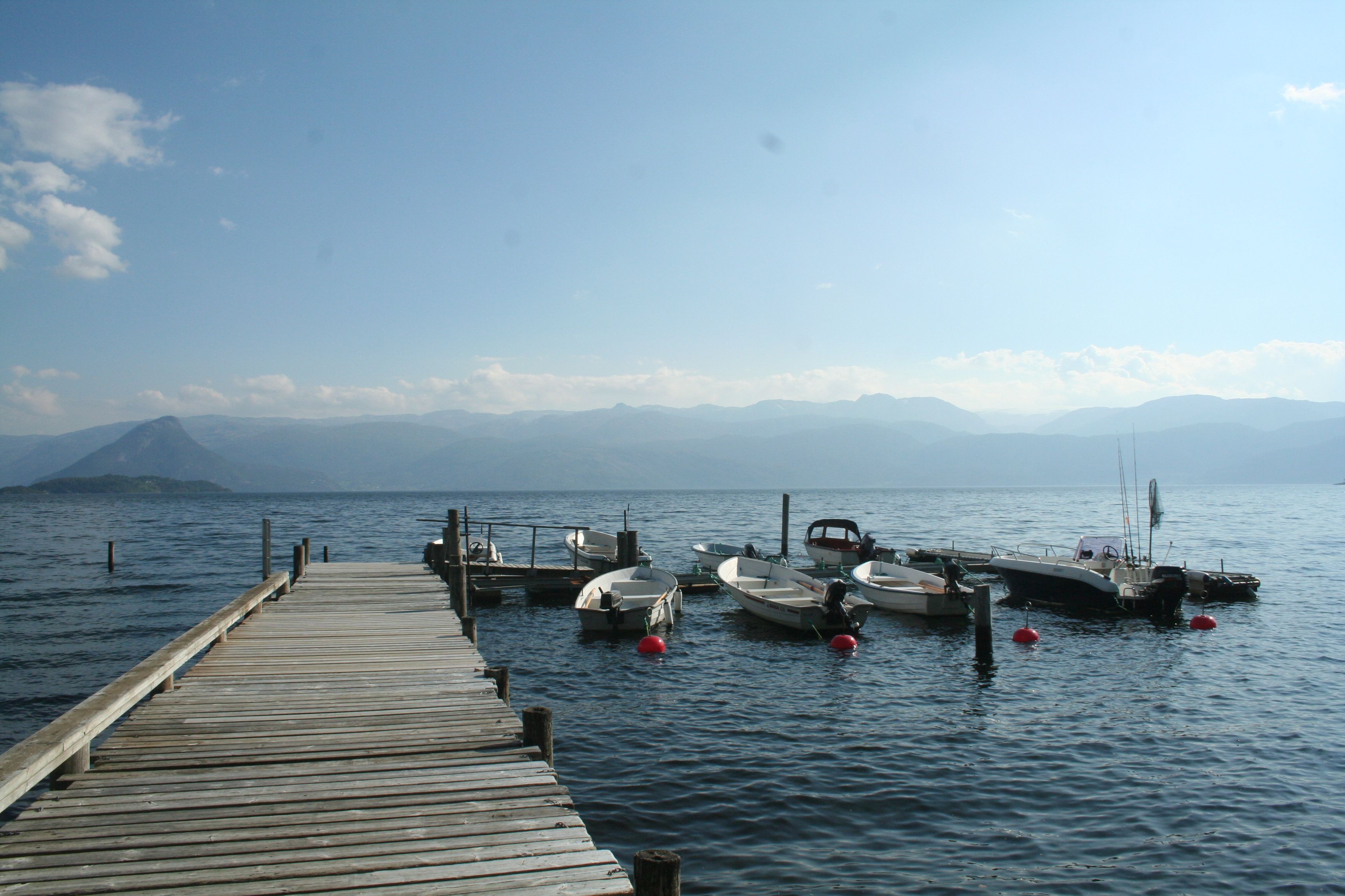 Brygge med småbåtar ved Hardanger Feriesenter med fjell og fjordlandskap.