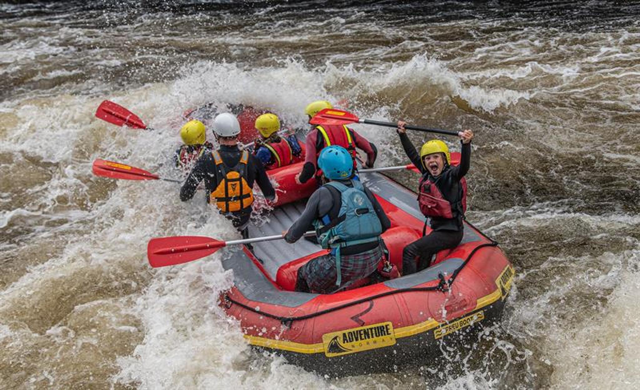 Rafting i Mandalselva, en glad gjeng i bølgene. Et barn som roper av glede og løfter åren over hodet