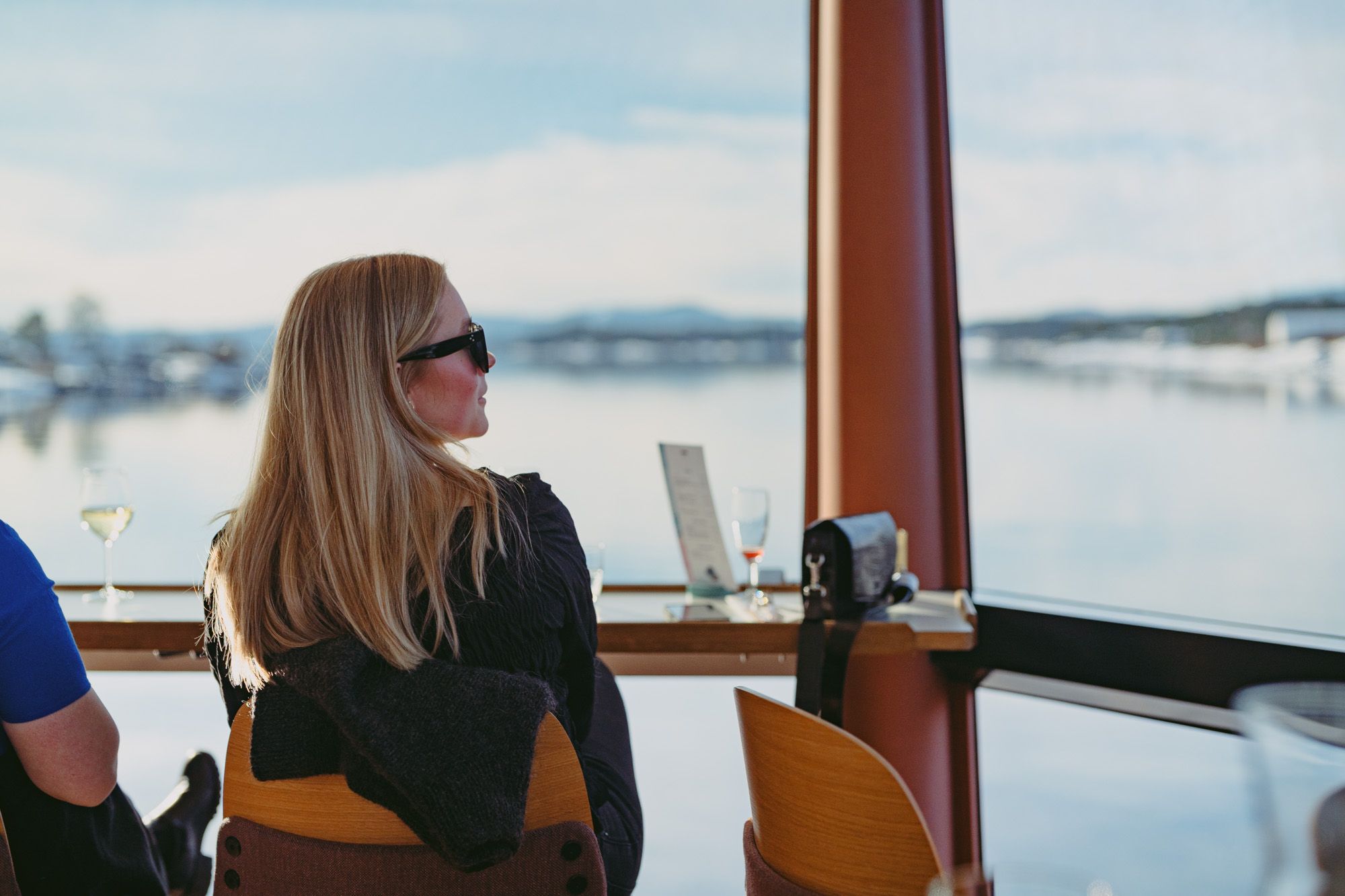 Girl sitting inside the boat, looking at the view through the panoramic window.